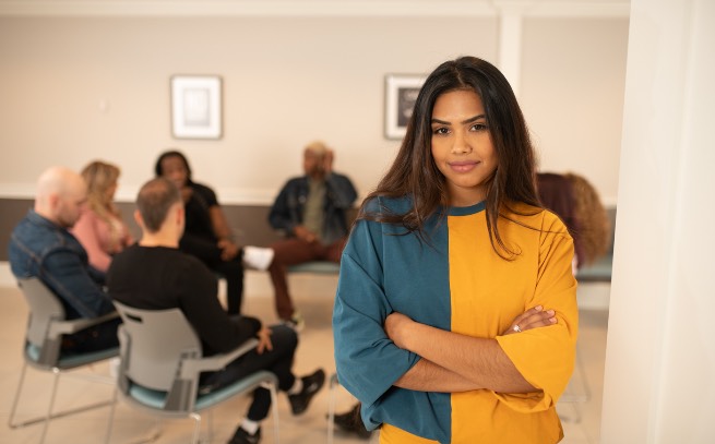 Girl standing in front of a therapy group in the background